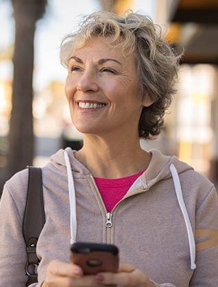 Smiling older woman outdoors holding cellphone